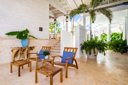 This covered lounge area features wooden loungers and potted plants offering a serene atmosphere.