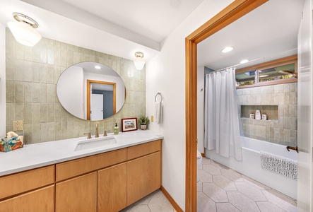 The primary ensuite offers a spacious vanity and separate shower/tub combo, perfect for unwinding after a day by the bay.