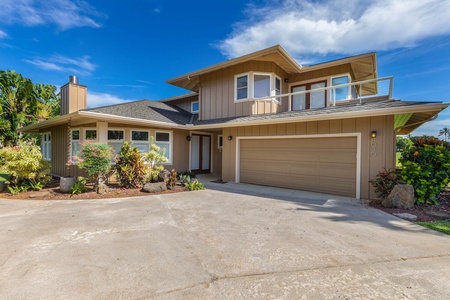 Exterior view of Pohaku Villa with spacious driveway, garage, and lush tropical surroundings.