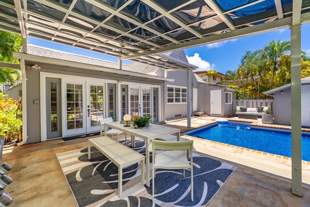 Tropical backyard retreat with sparkling pool, sun loungers, and lush palms framing the property. Brick patio and verdant lawn complete your private outdoor escape.