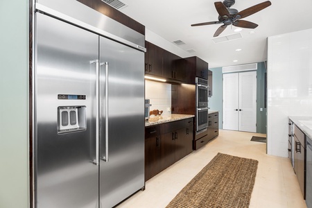 The fully equipped gourmet kitchen features sleek stainless steel appliances and rich dark cabinetry, perfect for creating memorable meals.