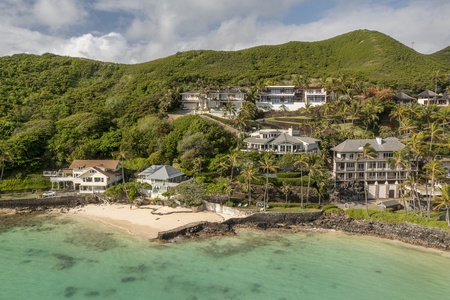 Aerial view of the property nestled against the mountains and steps away from the beach.