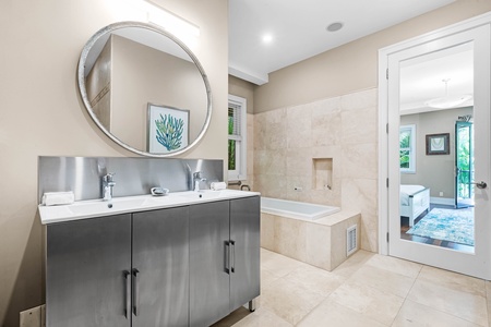En-suite bath with dual vanity, large mirror, and soaking tub.