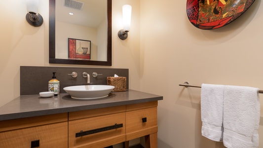 A half bath with sleek decorations and ample lighting.