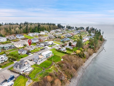 Coastal community nestled along the shoreline with well-maintained homes and tree-lined streets near the water's edge.