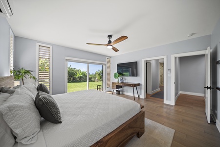 Primary suite offers king bed, garden slider, and wall-mounted Smart TV.