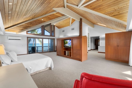 Bright bedroom with vaulted ceilings, cozy seating, and ocean views.