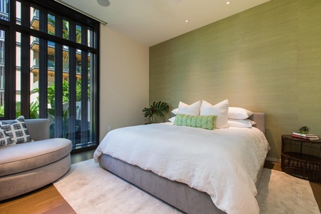 Retreat to the tranquil primary suite featuring a plush king bed, lanai access, and spectacular views of the ocean and Great Lawn.