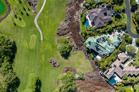 Aerial view of a home located next to a golf course, with pool and a serene and scenic setting for relaxation.