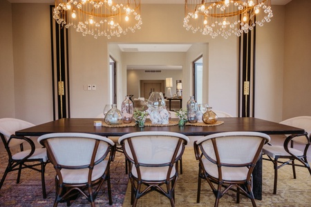 Sophisticated dining area featuring a long wooden table, stylish chairs, and decorative chandeliers.