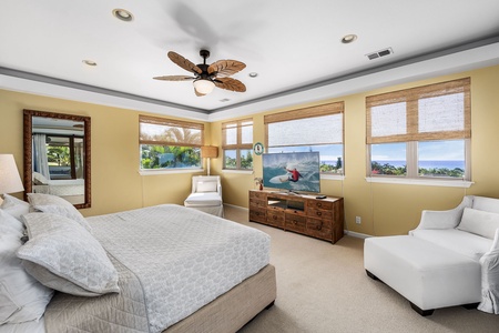 Primary bedroom with a king-sized bed, ocean views, and an inviting seating area for morning coffee