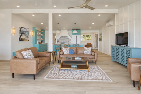 Sink into buttery leather seating in your open-concept living space, where coastal blue accents and warm wood create perfect harmony for relaxation.