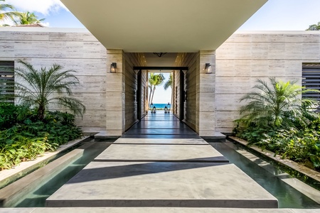 Stunning entrance with a pathway leading to the ocean, framed by lush greenery and modern architecture.