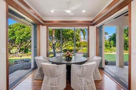 Indoor dining area with seating for six, surrounded by large windows offering serene garden views.