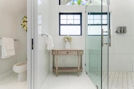 Spa-like guest bathroom with rainfall shower, stone accents, and garden view.