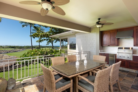 Outdoor dining area with a table for six, a built-in grill, and sweeping views of the golf course and greenery.
