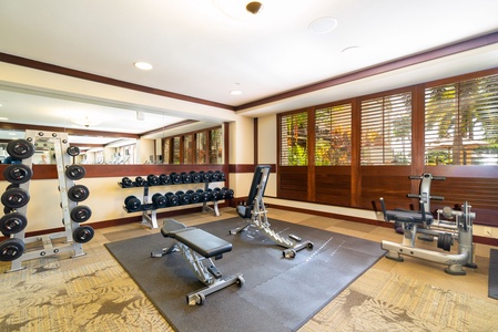 Stay fit during your getaway in this well-equipped fitness center, featuring free weights and machines with natural light streaming through wooden shutters.
