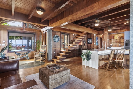The expansive great room showcases handcrafted timber beams, rich wood finishes, and an open-concept design that seamlessly connects the living, dining, and kitchen areas.