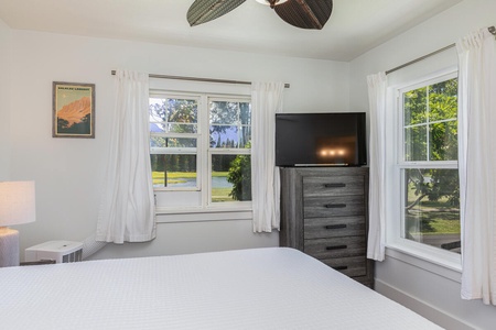 Serene guest bedroom with lush green views and soft white curtains for restful mornings.