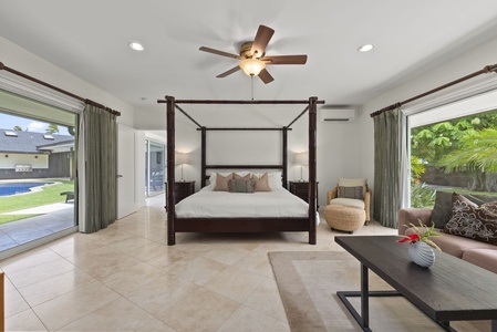 Spacious primary bedroom with canopy bed and seating area, a true retreat.