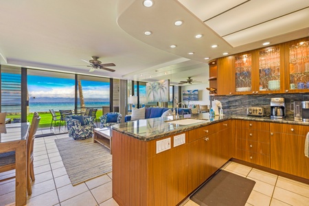 The open kitchen at Papakea L-106 features modern finishes and flows effortlessly into the living area and oceanfront lanai—perfect for relaxed island living