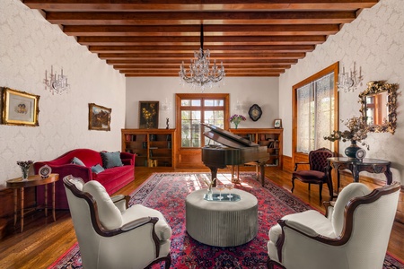 The formal living room, also an antique music room, features high-vaulted acoustic ceilings and luxury appointments, perfect for hosting elegant gatherings or enjoying quiet moments of relaxation.