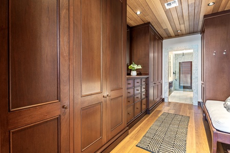 Your spacious walk-in closet offers abundant storage with custom wood cabinetry and warm lighting for organizing your vacation wardrobe in style.