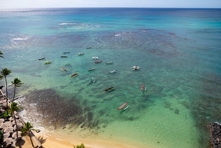 Aerial view showcasing pristine turquoise waters dotted with colorful boats along a palm-fringed coastline.