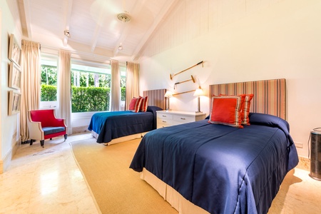 Bright and cheerful guest bedroom featuring double beds, and large windows allowing natural light.