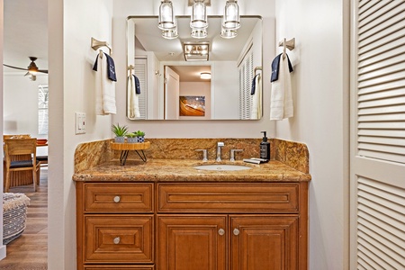 The bathroom at Mahana 1118 boasts granite counters, rich wood cabinetry, and modern fixtures.