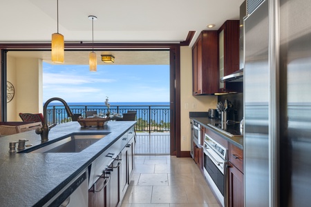 The kitchen is equipped with high-end stainless steel appliances, including a built-in oven, microwave, and a spacious refrigerator, all perfectly situated to enjoy the ocean view.