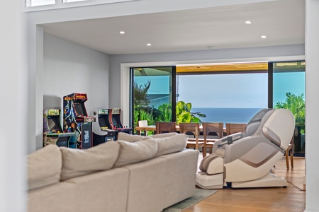 Expansive living area with ocean views, arcade games, and ample seating for entertainment.