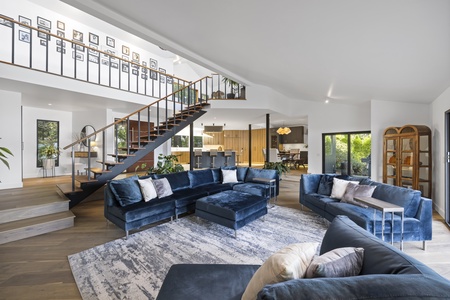 Gather with loved ones in the bright and airy living room featuring plush sectional sofas, a cozy fireplace, and two-story windows with lake views.