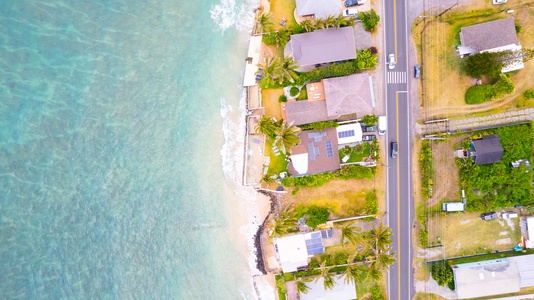 Aerial view of beachfront properties nestled along pristine turquoise waters and sandy coastline.