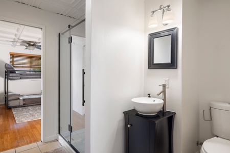 A compact guest bathroom with modern fixtures and walk-in shower serves the detached wing or overflow sleeping quarters.