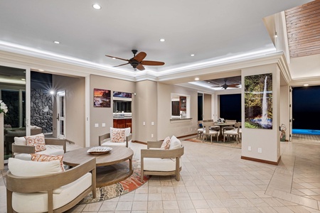 The pool illuminated at dusk, with the home lit behind it and the ocean just beyond.