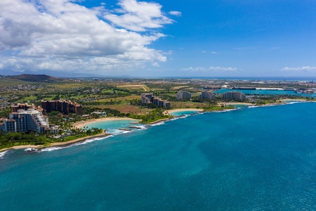 Stunning aerial view showcases the pristine coastline with turquoise waters, sandy beaches, and modern resort developments nestled along this tropical paradise.