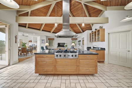 Cook gourmet meals in your spacious kitchen featuring warm wood cabinetry, professional-grade gas range, and stunning vaulted ceilings with exposed beams.