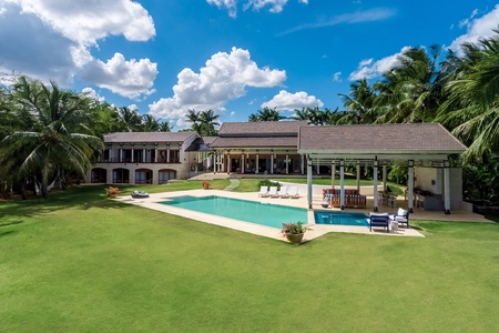 Experience a luxurious retreat in this estate with a large pool, expansive lawn, and tropical surroundings.