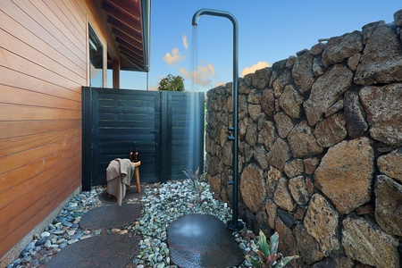 Secluded outdoor shower surrounded by lava rock and tropical greenery—an authentic island experience under open skies.