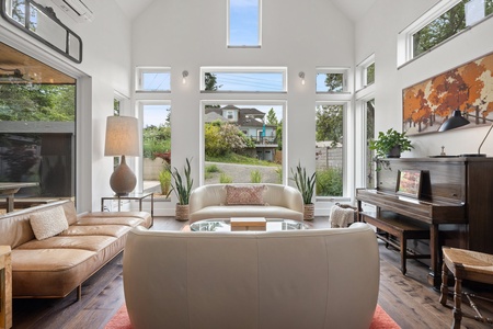 Sunny main living area with large windows, high ceilings, and eclectic art—perfect for gathering.