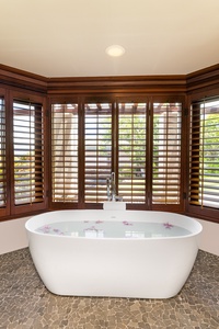 Soak in the deep freestanding tub framed by tropical gardens and warm island light.