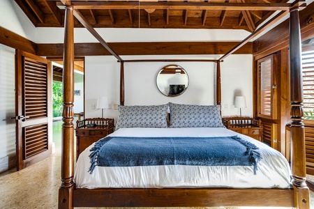 The high vaulted-ceiling primary suite features a four poster king bed and TV.