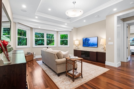 Media lounge with sectional seating, TV, and serene windowscape.