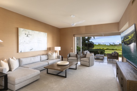 Downstairs media room with plush furnishings, two corner walls of pocket doors, large deck, and private manicured lawn beyond