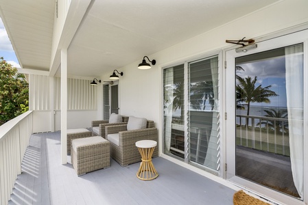 Covered outdoor lounge with cozy wicker furniture, offering the perfect shady retreat steps from the sand and surf.