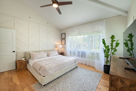 Bright primary bedroom featuring a king-size bed and modern accents.