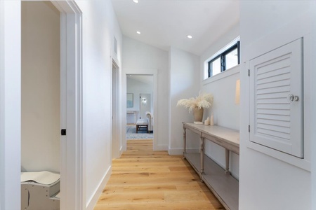 Bright hallway with custom cabinetry and warm wood floors leading to private quarters.