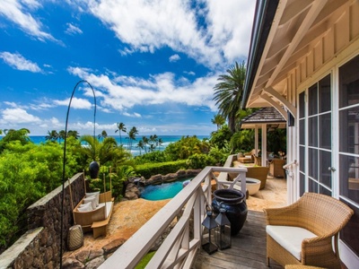 Elevated lanai with views across the pool, palms, and ocean beyond.