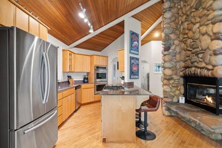 Gather around your spacious gourmet kitchen where granite counters and premium appliances invite memorable meal preparation beside a cozy stone fireplace.